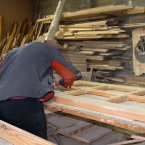 a person working on a wooden door in a workshop