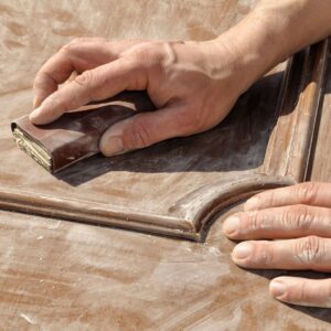 a person sanding a wooden door