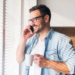 Person smiling while making a phone call and holding a mug